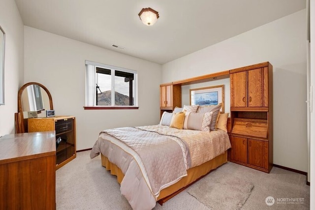 bedroom with baseboards, visible vents, and light colored carpet