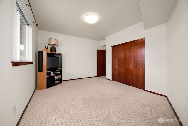 unfurnished bedroom with a closet, baseboards, and carpet flooring