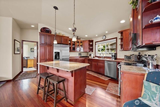 kitchen featuring stainless steel appliances, a kitchen island, open shelves, dark wood finished floors, and decorative light fixtures