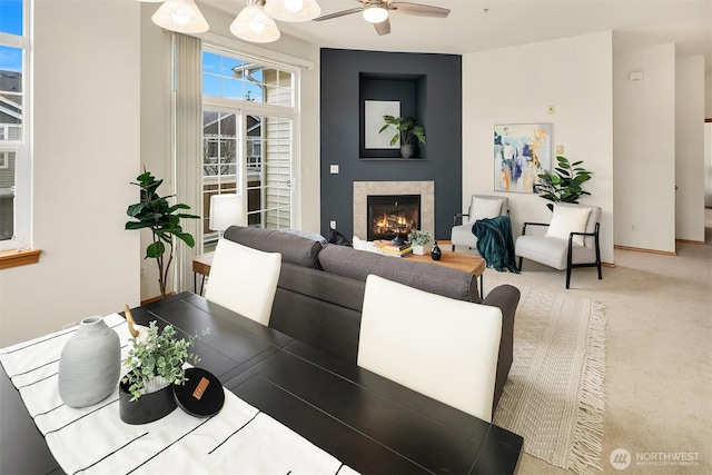 carpeted living area featuring baseboards, a ceiling fan, and a tiled fireplace