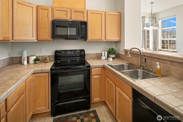 kitchen with tile counters, pendant lighting, black appliances, and a sink