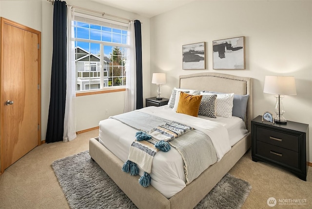 bedroom with light colored carpet and baseboards