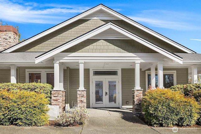 property entrance with french doors, a chimney, and a shingled roof