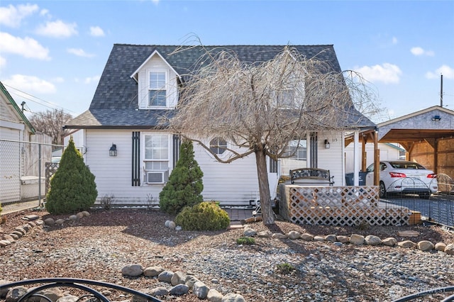 view of front of home featuring a carport, a shingled roof, and fence