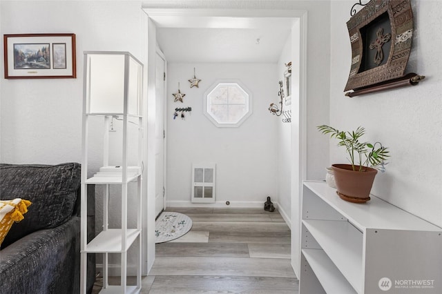 mudroom featuring heating unit, baseboards, and wood finished floors