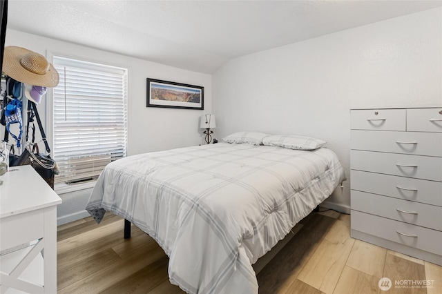 bedroom with lofted ceiling and light wood-style flooring