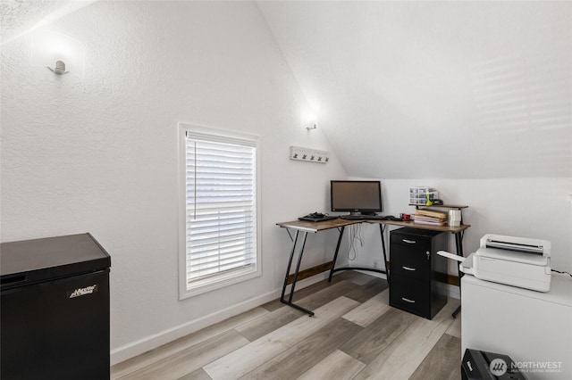 home office with lofted ceiling, baseboards, and light wood-type flooring