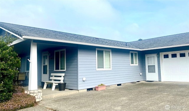 view of side of home with a garage, concrete driveway, crawl space, and roof with shingles