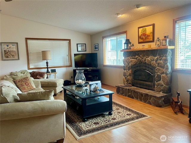 living room with a fireplace, vaulted ceiling, a textured ceiling, and wood finished floors