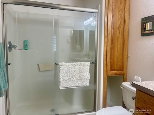 bathroom featuring a stall shower, vanity, and toilet