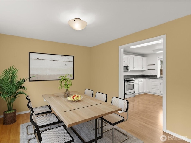 dining space featuring light wood finished floors and baseboards