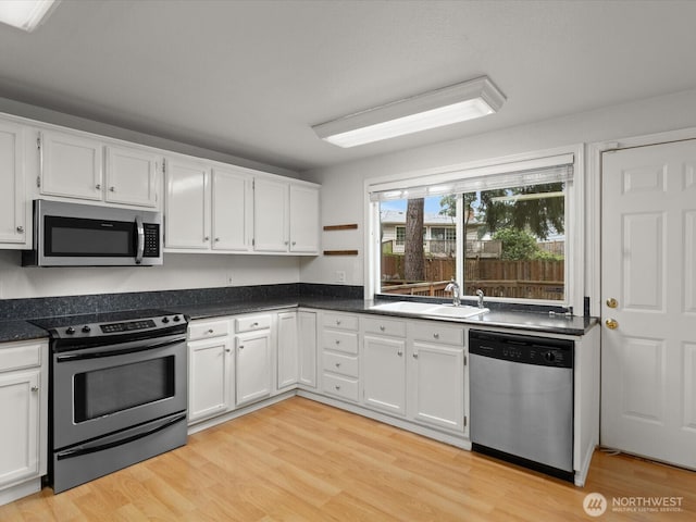 kitchen with light wood-style floors, appliances with stainless steel finishes, white cabinets, and a sink