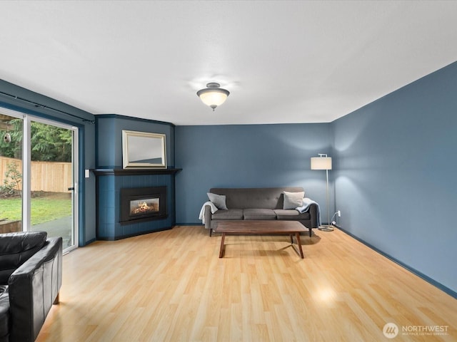 living area featuring a tiled fireplace and wood finished floors