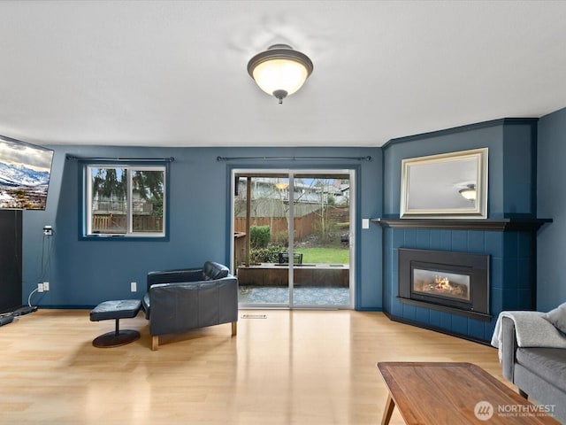 sitting room with a tile fireplace and wood finished floors