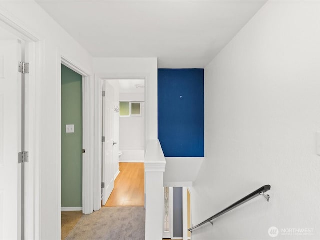 hall featuring baseboards, carpet flooring, and an upstairs landing