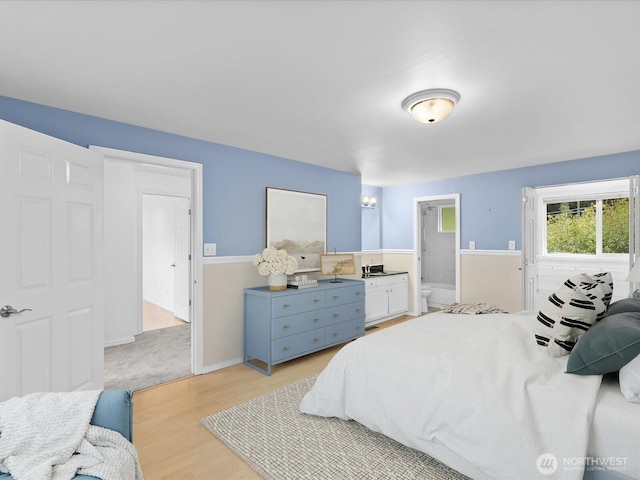 bedroom featuring light wood-type flooring, ensuite bath, and baseboards