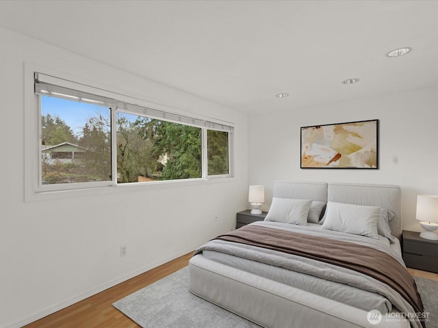 bedroom with baseboards, wood finished floors, and recessed lighting