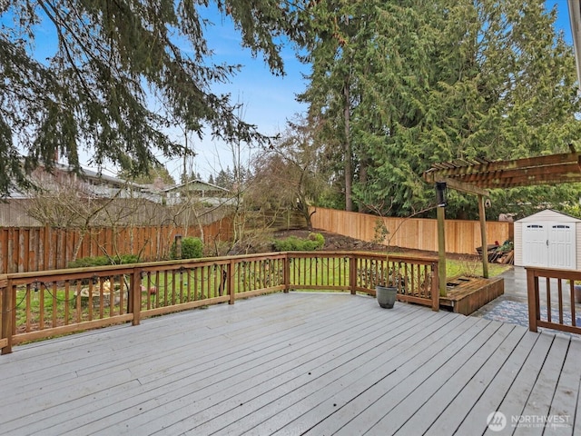 wooden terrace featuring a fenced backyard, an outdoor structure, and a storage unit