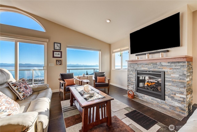 living room with a fireplace, vaulted ceiling, baseboards, and wood finished floors