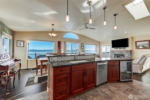 kitchen with vaulted ceiling with skylight, wine cooler, a sink, dishwasher, and pendant lighting