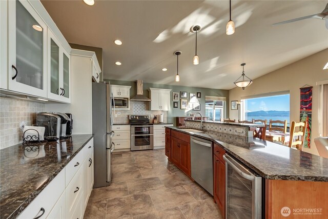 kitchen with decorative backsplash, wall chimney exhaust hood, wine cooler, stainless steel appliances, and a sink