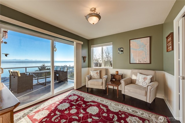 sitting room with a wainscoted wall, a water view, and wood finished floors