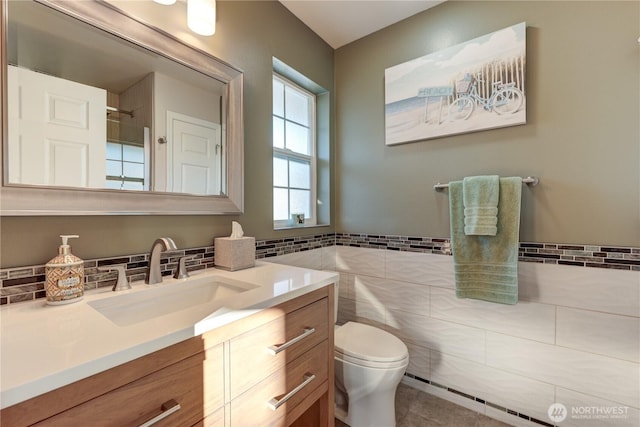 full bath featuring toilet, vanity, tile walls, wainscoting, and tile patterned floors