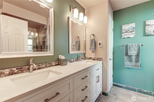 bathroom featuring tile patterned flooring, a sink, decorative backsplash, and double vanity