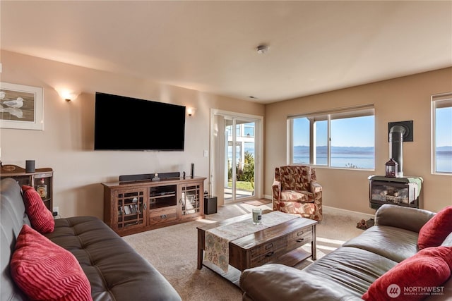 carpeted living area with a wood stove and baseboards