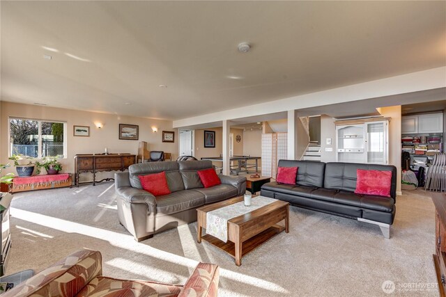 living room with stairway and light colored carpet