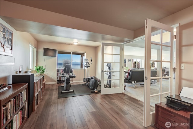 workout room featuring french doors, wood finished floors, and baseboards