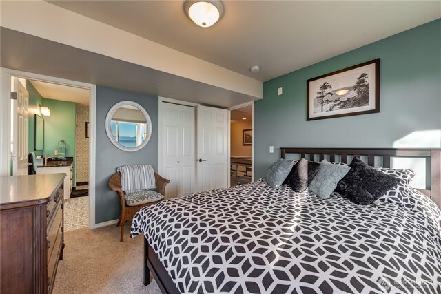 bedroom featuring light carpet, a closet, ensuite bath, and baseboards