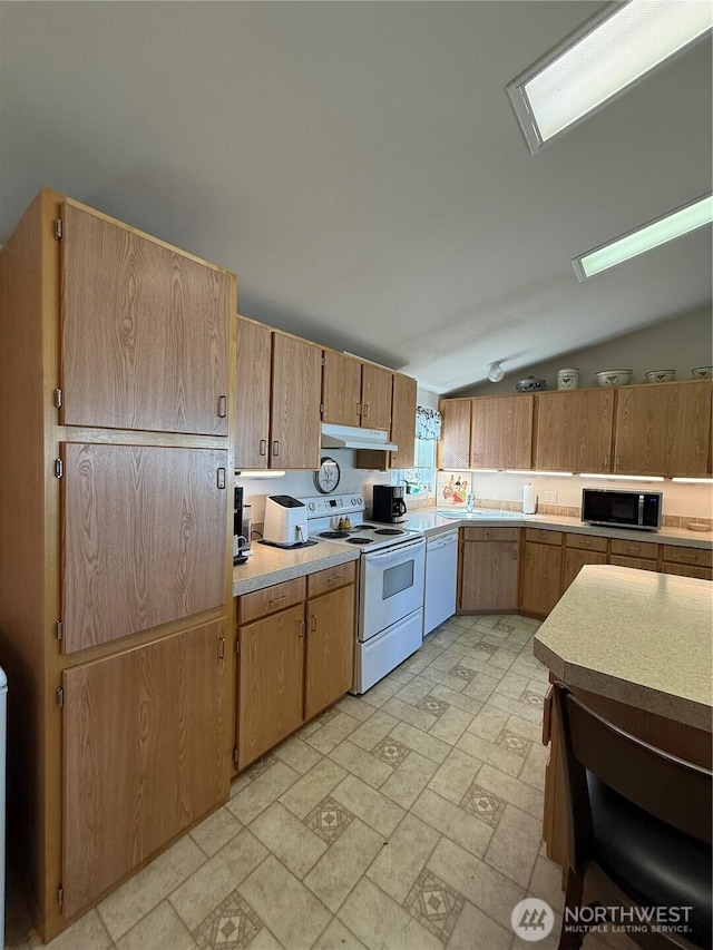 kitchen featuring white appliances, light countertops, vaulted ceiling, and under cabinet range hood