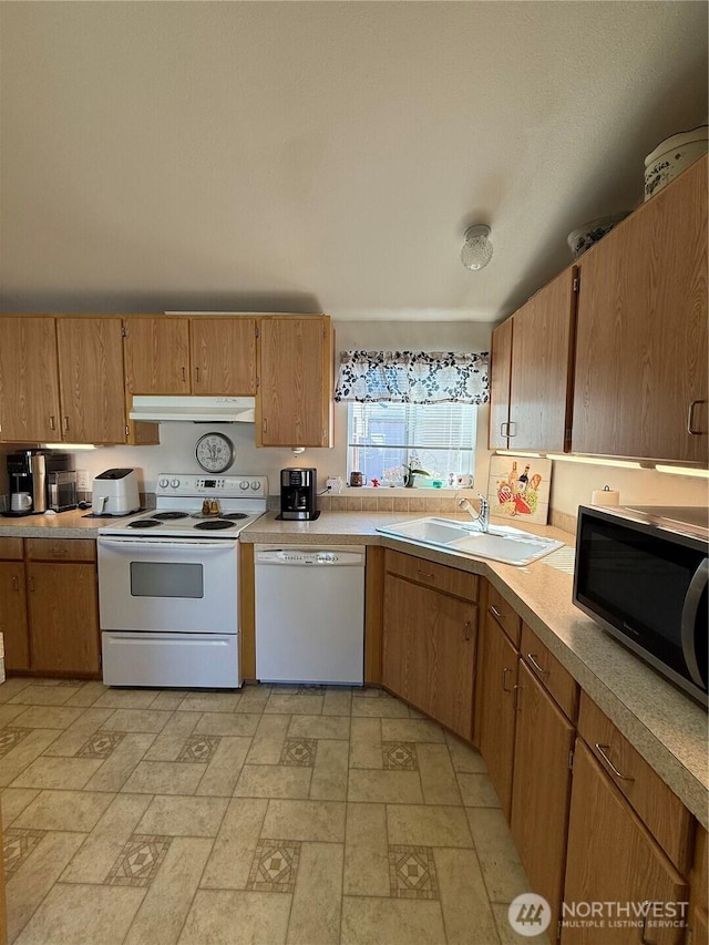 kitchen featuring white appliances, under cabinet range hood, light countertops, and a sink