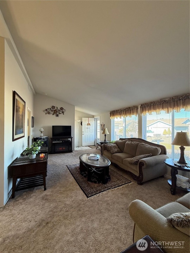 carpeted living area with lofted ceiling