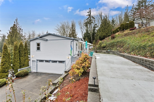 view of side of home with aphalt driveway, stairway, and an attached garage