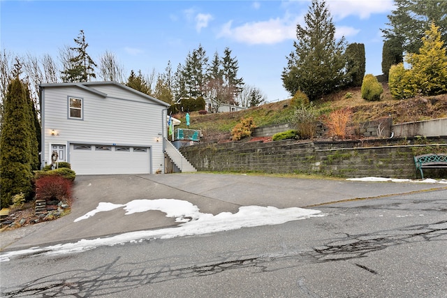 view of property exterior with driveway, an attached garage, fence, and stairway