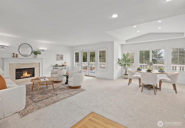 carpeted living room with a high end fireplace, french doors, vaulted ceiling, and recessed lighting