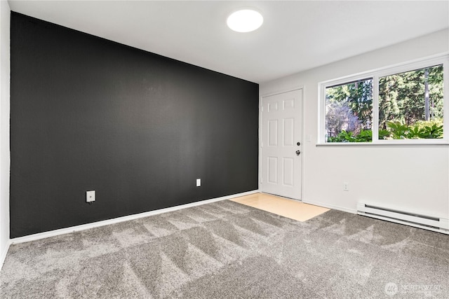 unfurnished room featuring a baseboard heating unit, carpet, and baseboards