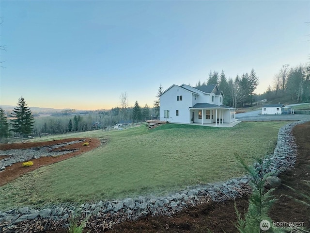 back of house at dusk with a patio and a yard