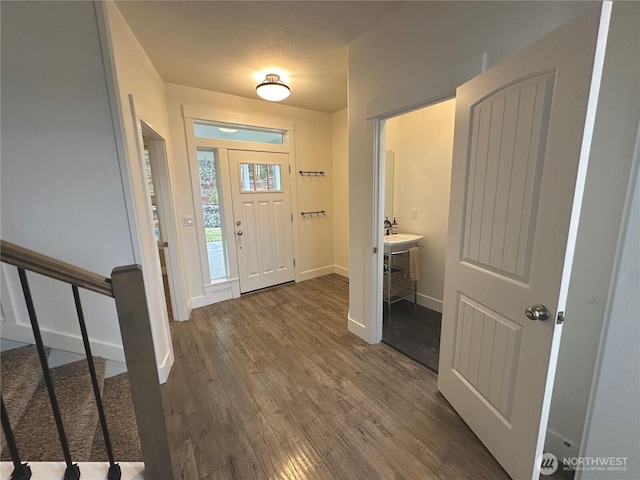 foyer entrance featuring stairway, baseboards, and wood finished floors