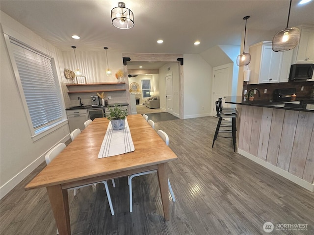 kitchen featuring dark countertops, black microwave, white cabinets, and wood finished floors