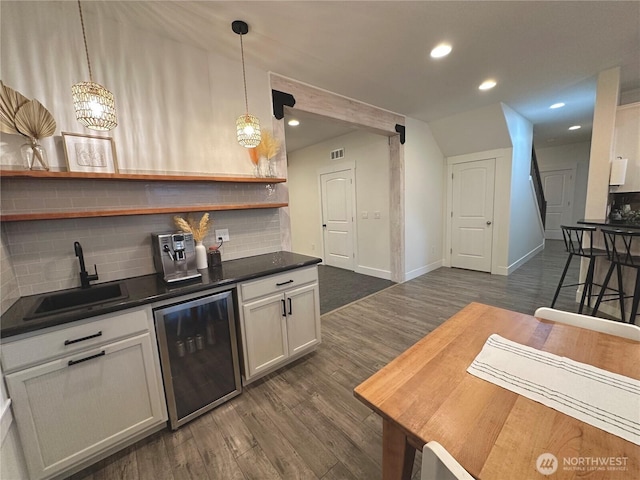 bar with dark wood-style flooring, recessed lighting, backsplash, a sink, and beverage cooler