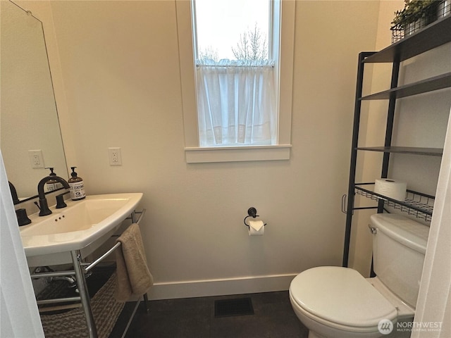 half bathroom with toilet, baseboards, visible vents, and a sink