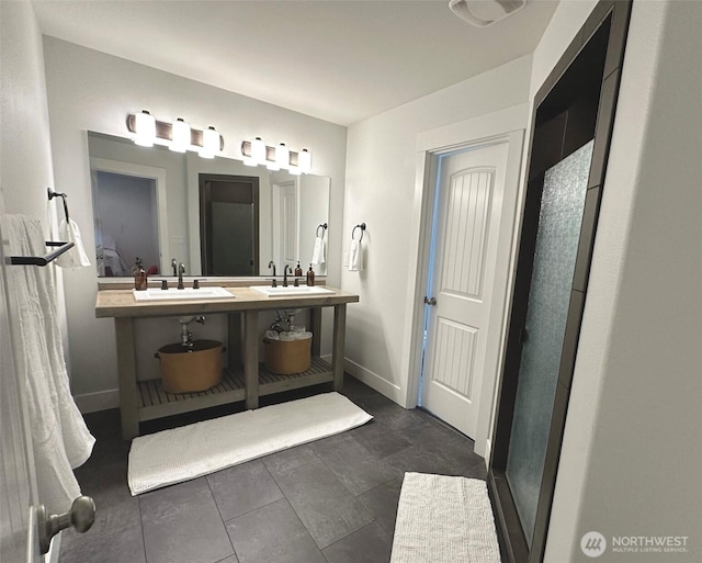 bathroom with a stall shower, baseboards, and a sink