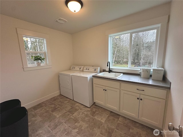 washroom with a wealth of natural light, washer and dryer, cabinet space, and a sink