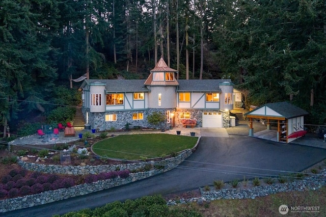 view of front facade with driveway, a garage, stone siding, a carport, and a front yard