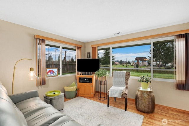 living area featuring wood finished floors, visible vents, and a healthy amount of sunlight