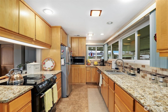 kitchen with light tile patterned floors, decorative backsplash, light stone counters, stainless steel appliances, and a sink