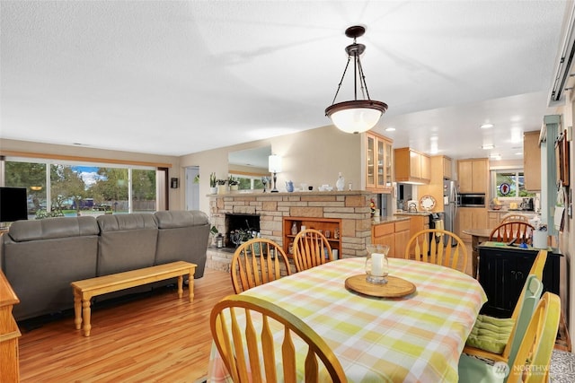 dining room featuring a textured ceiling, light wood finished floors, a fireplace, and recessed lighting